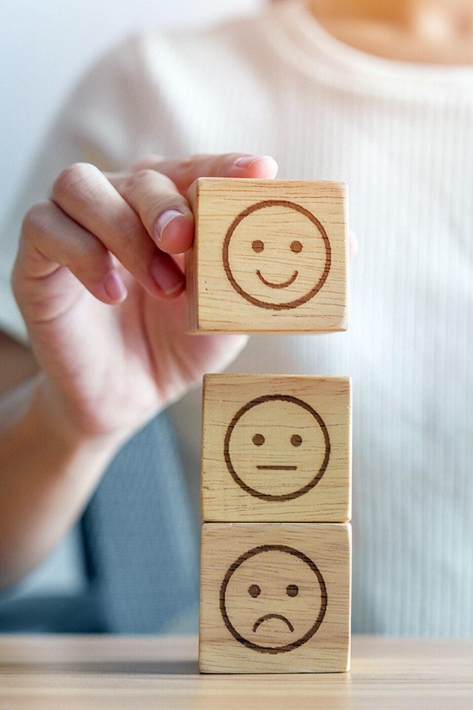 a stack of wooden blocks with faces of different happiness levels to express customer feedback.